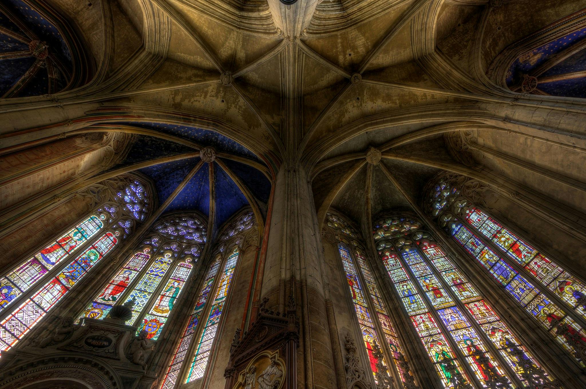 Gothic cathedral interior, showing vaulted ceiling and large, colorful stained glass windows.