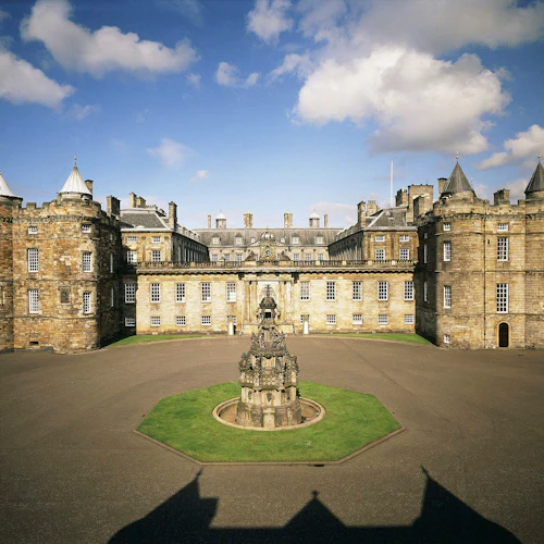 Historiskt stenslott med cylindriska torn, symmetrisk struktur och en central innergård med en utsmyckad fontän.