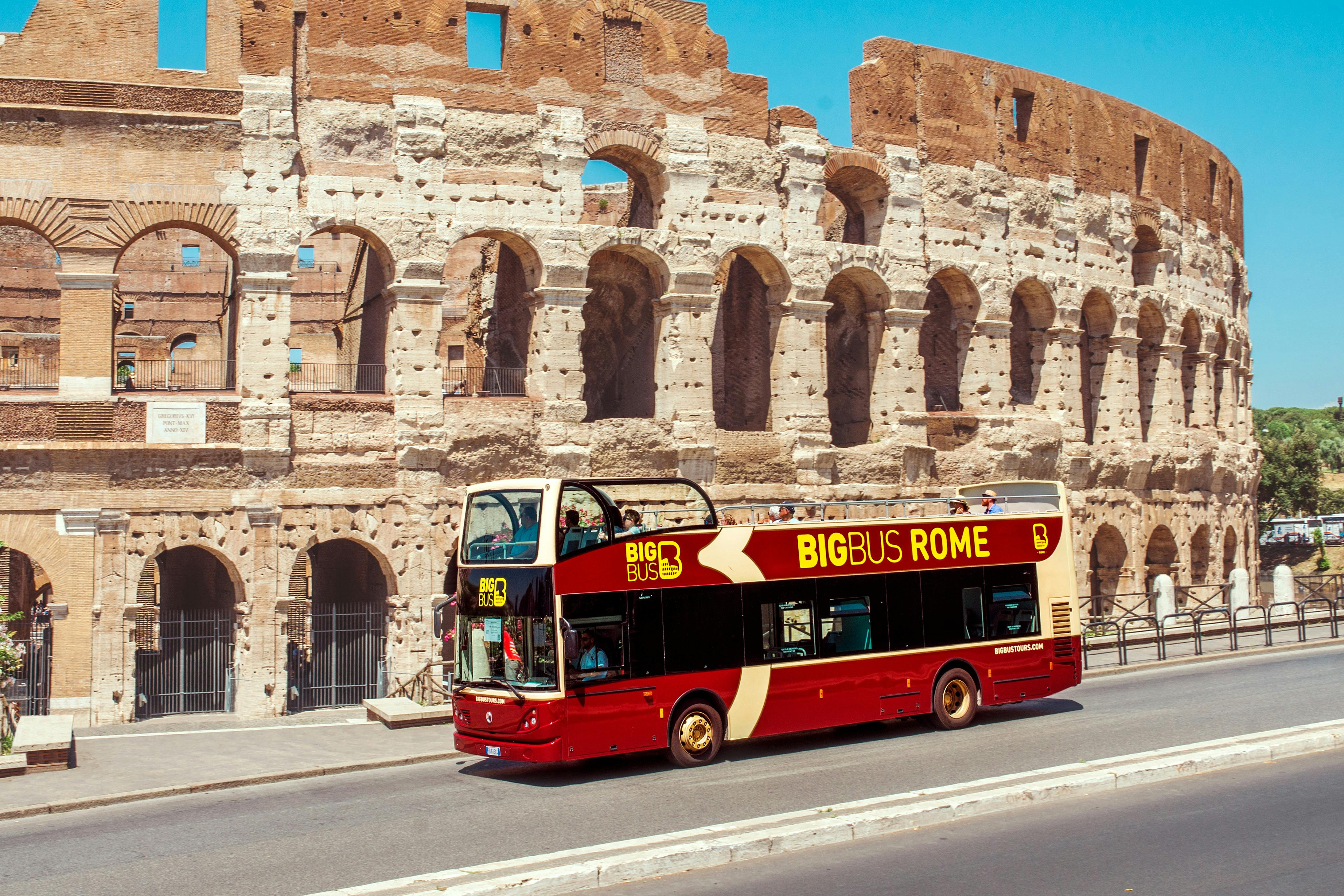 A red double-decker tourist bus labeled 'Big Bus Rome' parked in front of the Colosseum in Rome, Italy, under a clear blue sky.