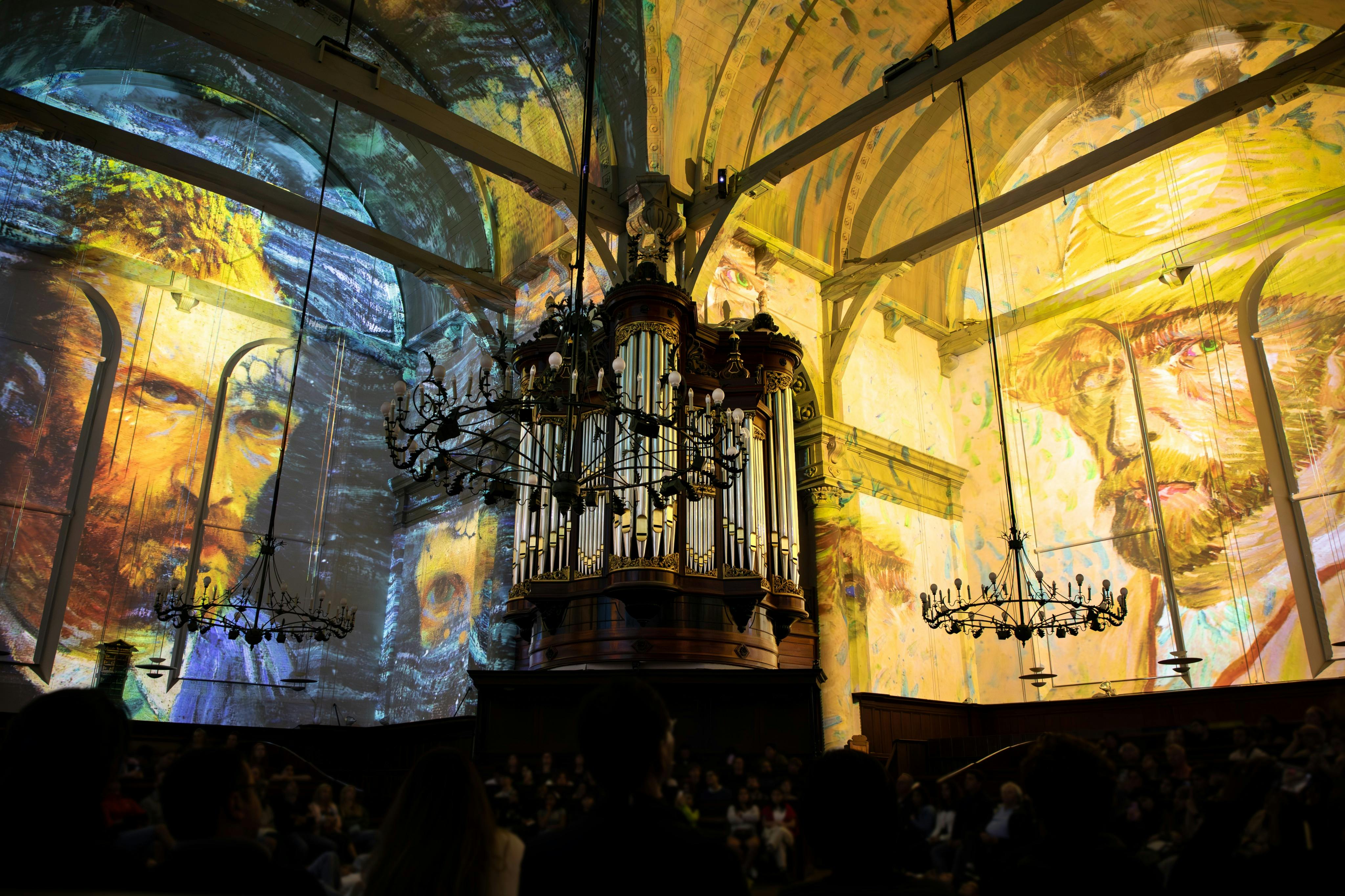 ステンドグラスの窓、シャンデリア、大きなパイプオルガンを備えた華やかな教会内部。 壁にカラフルなアートワークを投影。