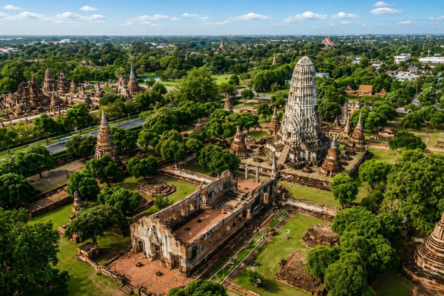 Aerial view of a historical temple complex with ancient structures and greenery under a blue sky.