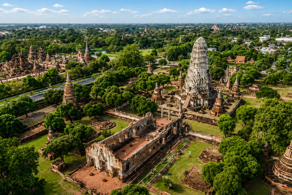 Aerial view of a historical temple complex with ancient structures and greenery under a blue sky.