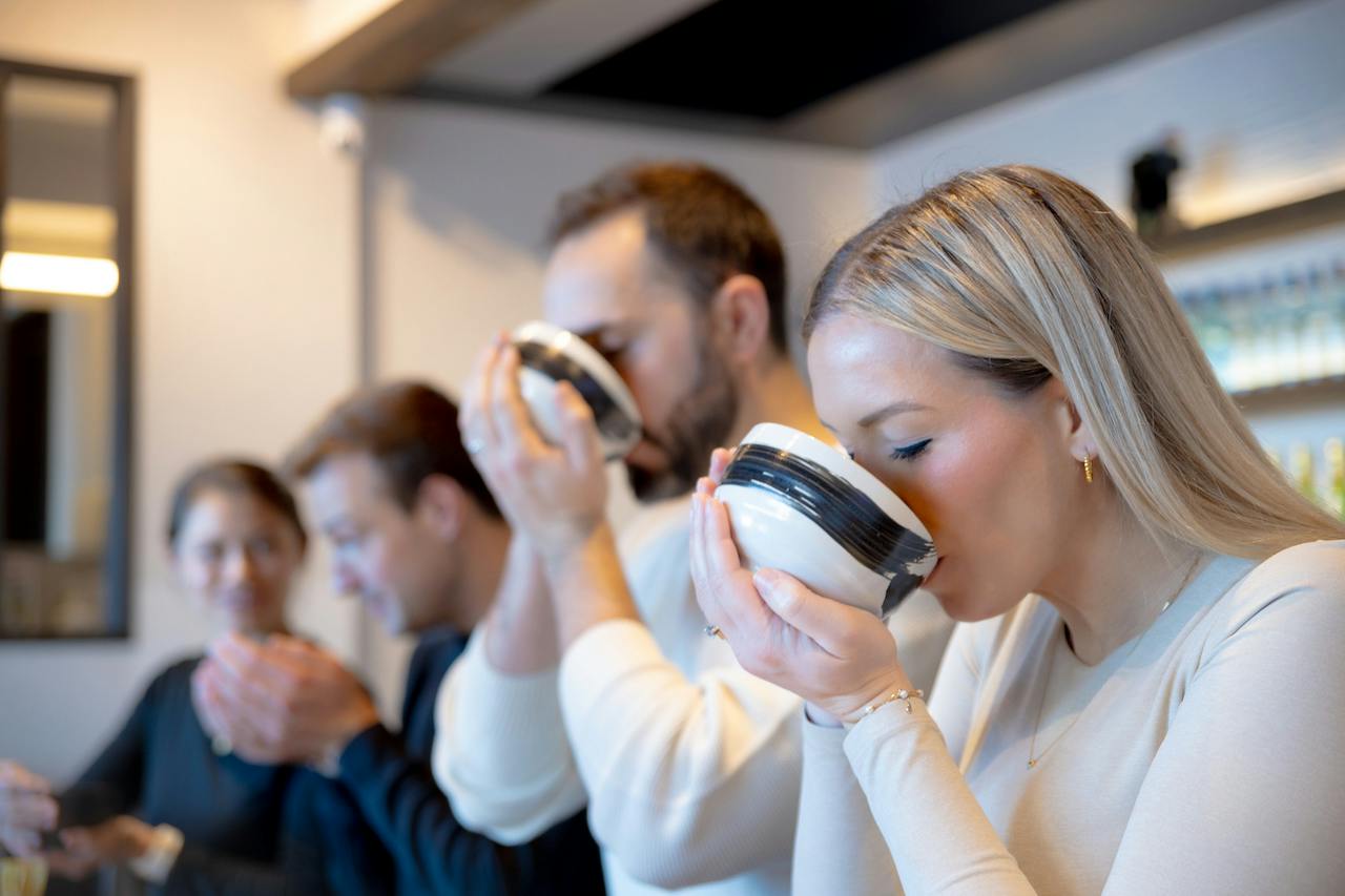 People drinking from bowls in a modern indoor setting.