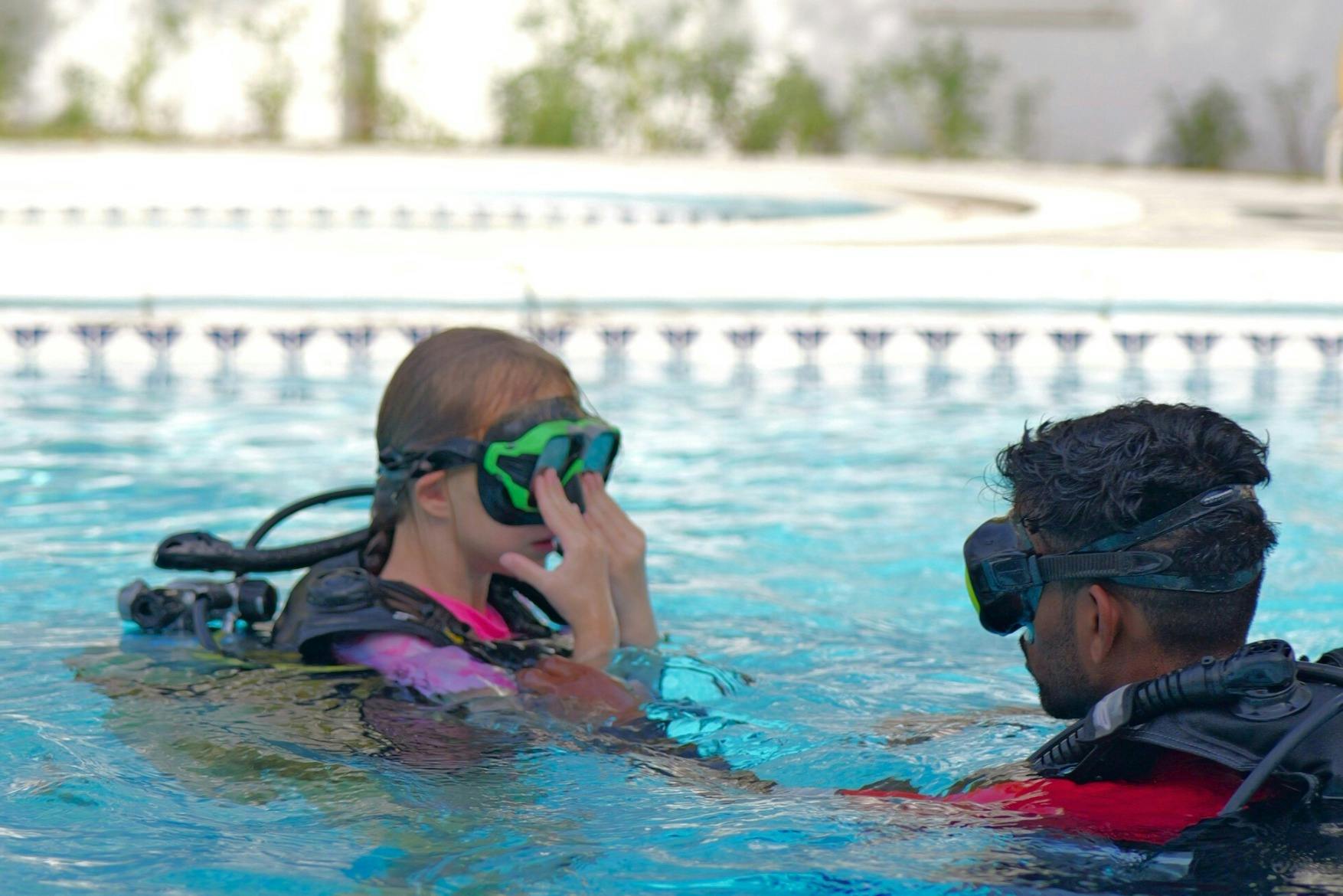 Δύο άτομα σε μια πισίνα που φορούν μάσκα κολύμβησης με αναπνευστήρα, με το ένα να φαίνεται ότι προσαρμόζει τη μάσκα του ενώ το άλλο κοιτάζει.