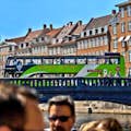 Ônibus verde de dois andares Hop On-Hop Off atravessando a ponte Nyhavn em Copenhague.