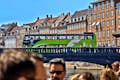 Autobús de dos pisos de Green Hop On-Hop Off que travessa el pont de Nyhavn a Copenhaguen.