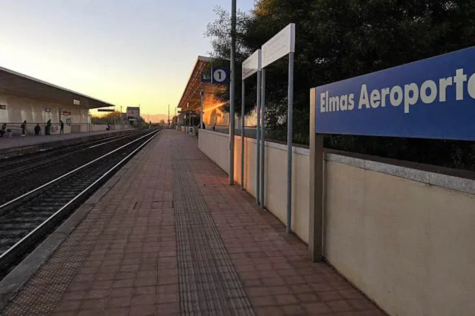 Empty train platform at sunset with "Elmas Aero" sign and tracks to the left. No people are present.