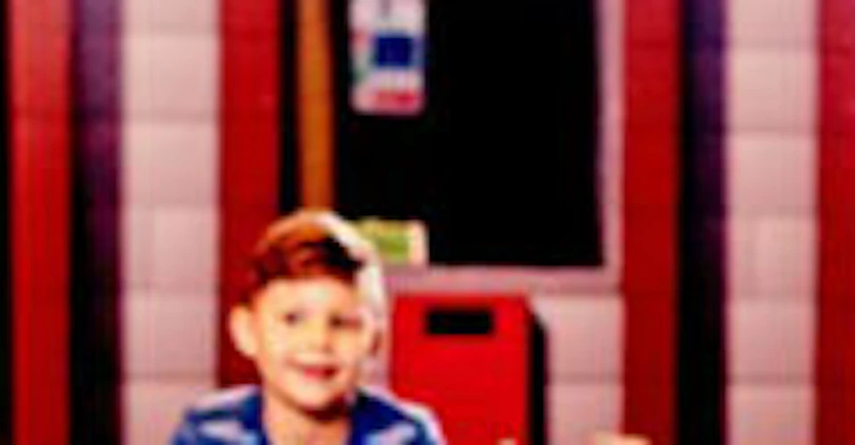 Children driving small police-themed ride-on cars inside a play area, smiling and having fun.