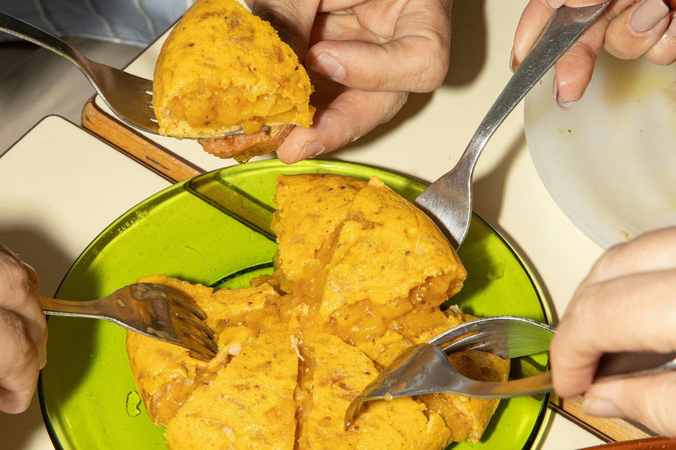 Les mains se partagent la tortilla espagnole traditionnelle, un plat de base des tapas.