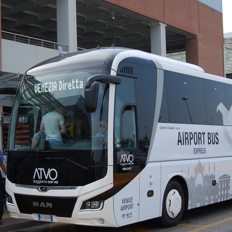 「VENEZIA Diretta」と「ATVO」というラベルの付いた白い空港バスがターミナルビルに駐車されており、入口付近には数人が駐車していました。