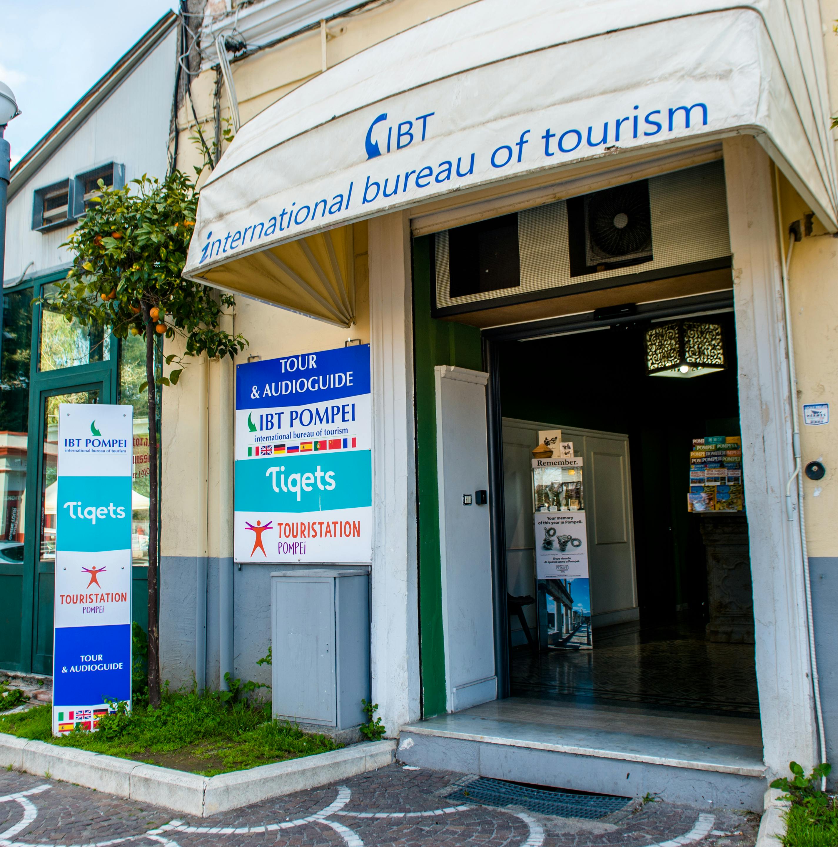 Entrance of the International Bureau of Tourism with signage for tours and audioguides, located on a street corner.