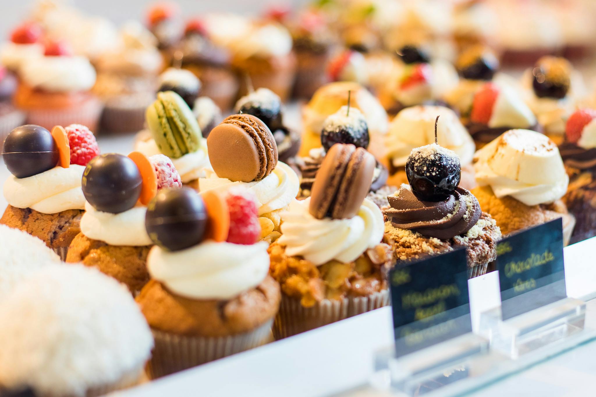 베이커리 세팅의 트레이에 마카롱, 과일, 초콜릿을 얹은 다양한 장식 컵케이크.