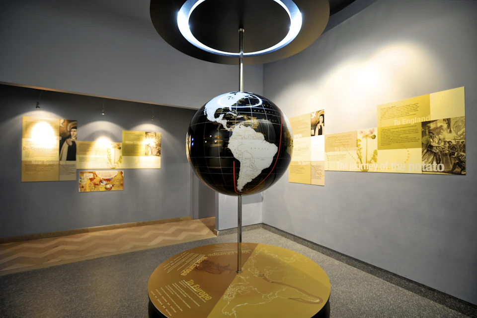 A museum exhibit featuring a large globe with highlighted text and diagrams on the surrounding walls and display table.