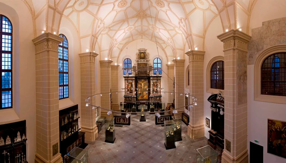 A spacious, elegant museum interior with tall arched ceilings, displays of artifacts in glass cases, and intricate wall decorations.