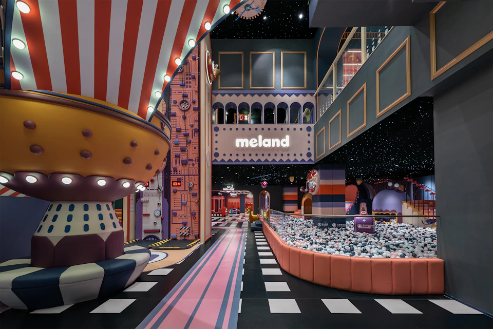 A colorful indoor play area with themed decor, a ball pit, and a sign reading "meland" under a star-like ceiling.