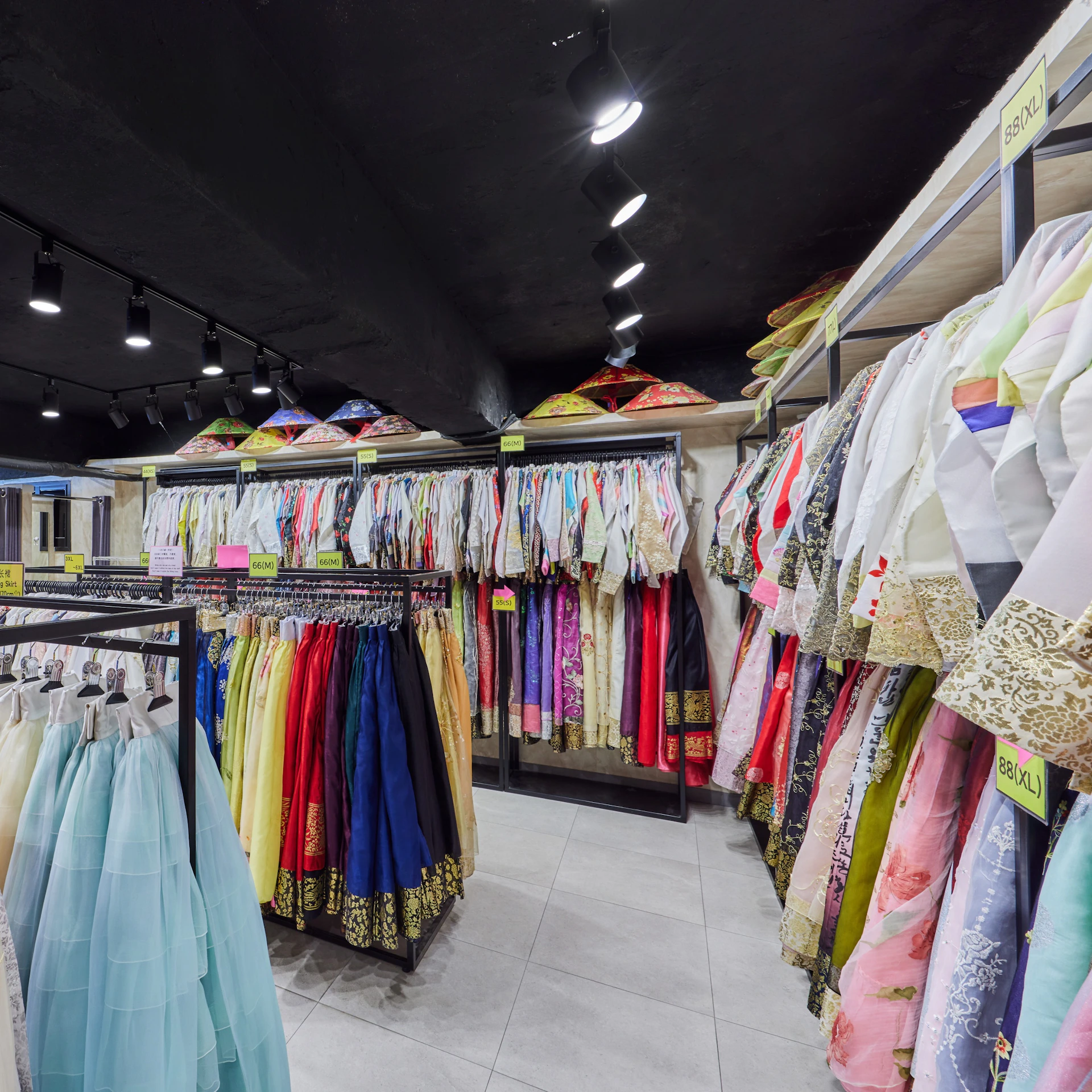A clothing store interior showcasing colorful traditional garments hung on racks and shelves under ceiling lights.