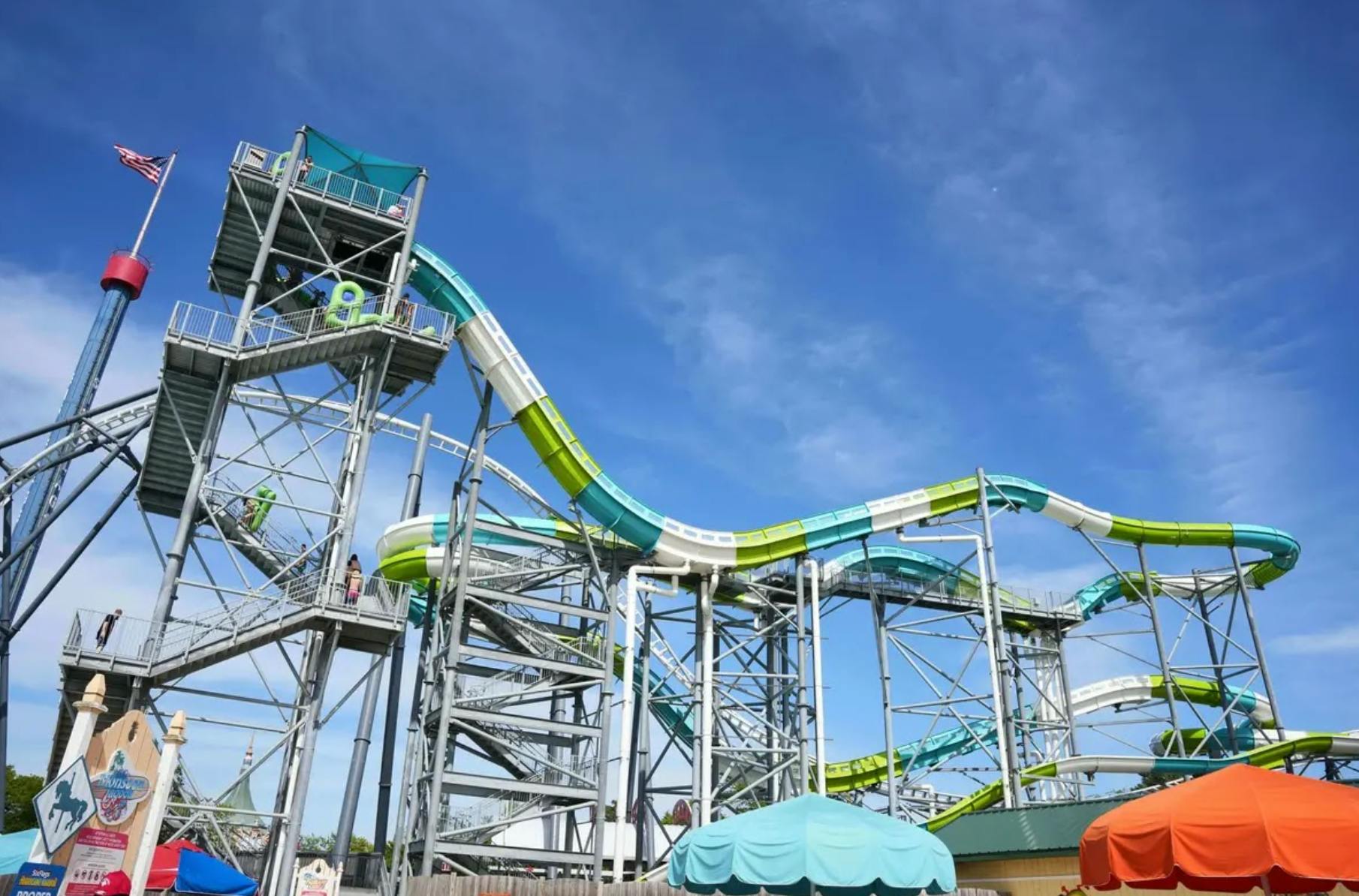 맑고 푸른 하늘 아래 금속 구조로 지지되는 녹색과 파란색 섹션이 있는 높은 워터 슬라이드.
