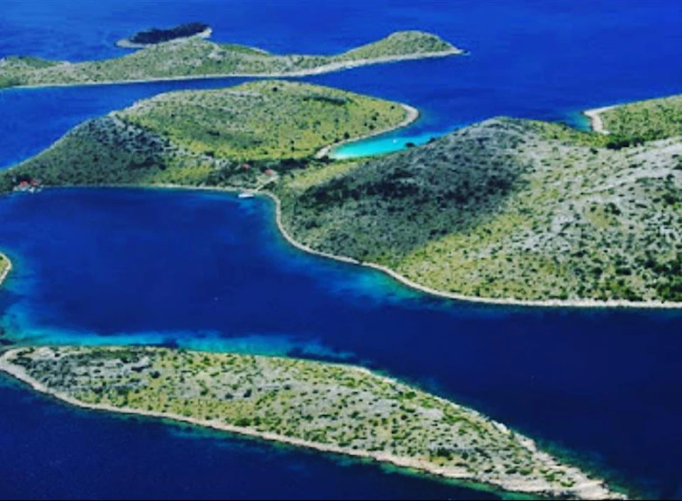 Aerial view of several green, hilly islands surrounded by deep blue water.