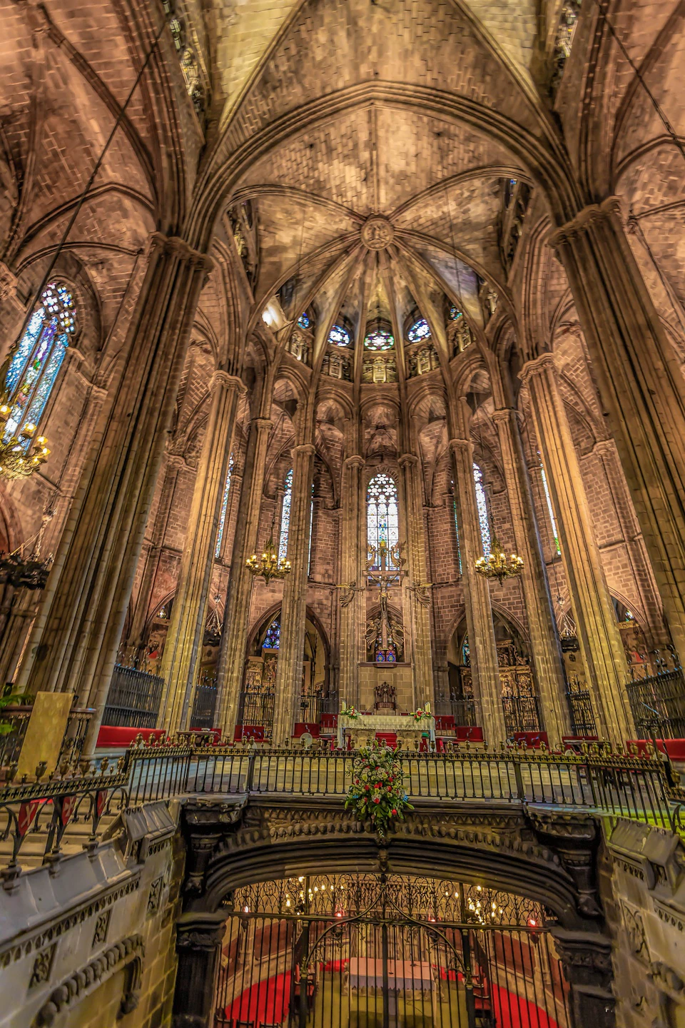 An interior view of a grand cathedral with tall arches, intricate stained glass windows, and ornate chandeliers.