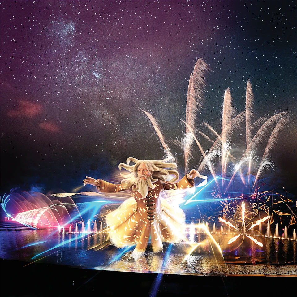 A performer in a glowing outfit amidst a vibrant light and fireworks display, with a starry sky in the background.