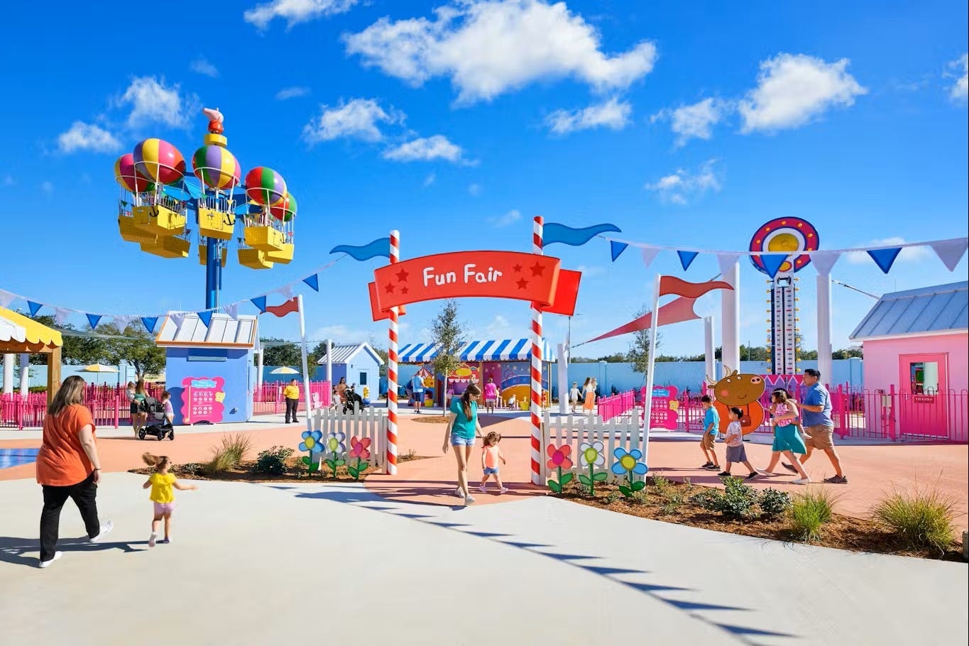 A colorful amusement park entrance with a red arch reading 'Fun Fair,' surrounded by rides, decorations, and visitors.