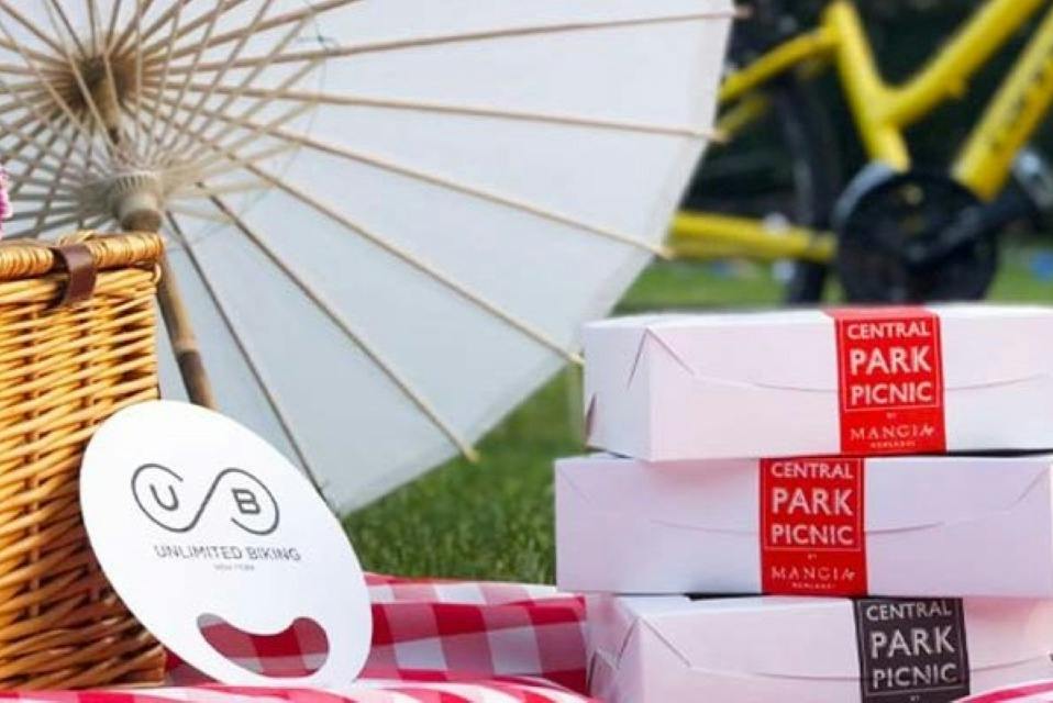 A picnic setup with a white parasol, stacked boxes labeled "Central Park Picnic," and part of a bicycle visible.