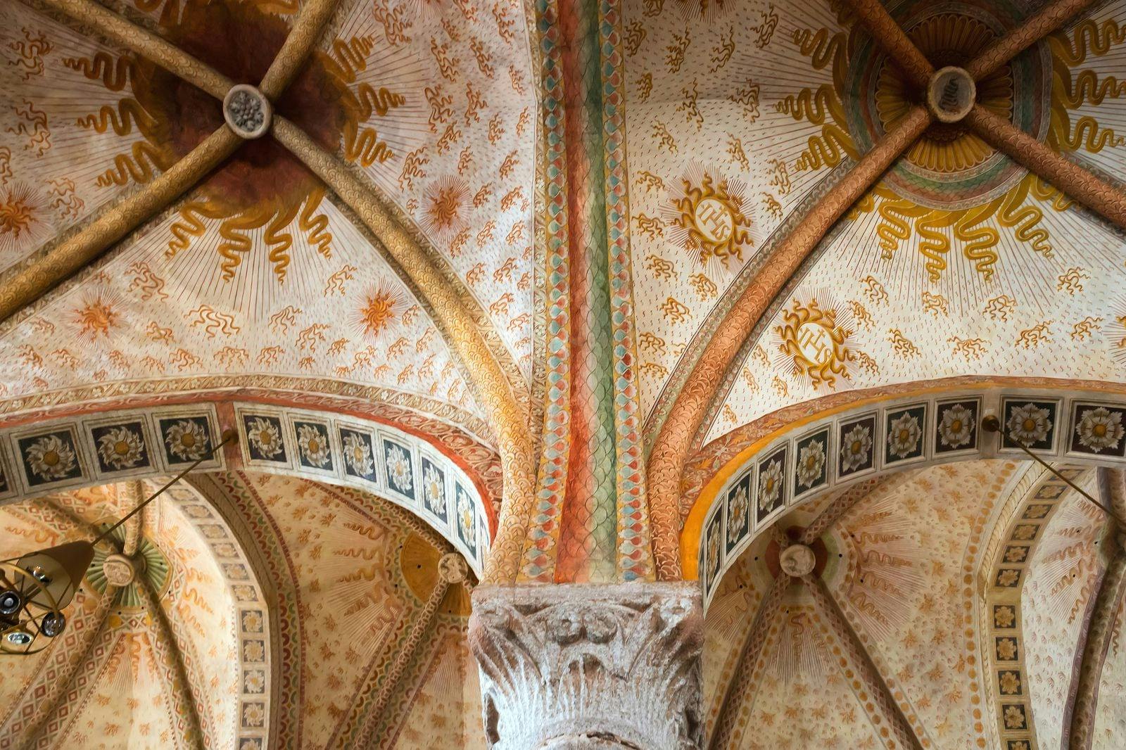 Ornate ceiling with intricate patterns, colorful arches, and detailed frescoes, featuring classical architectural design.