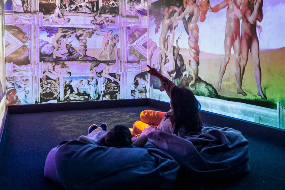 Two people lying on beanbags in an immersive projection room with Italian Renaissance content
