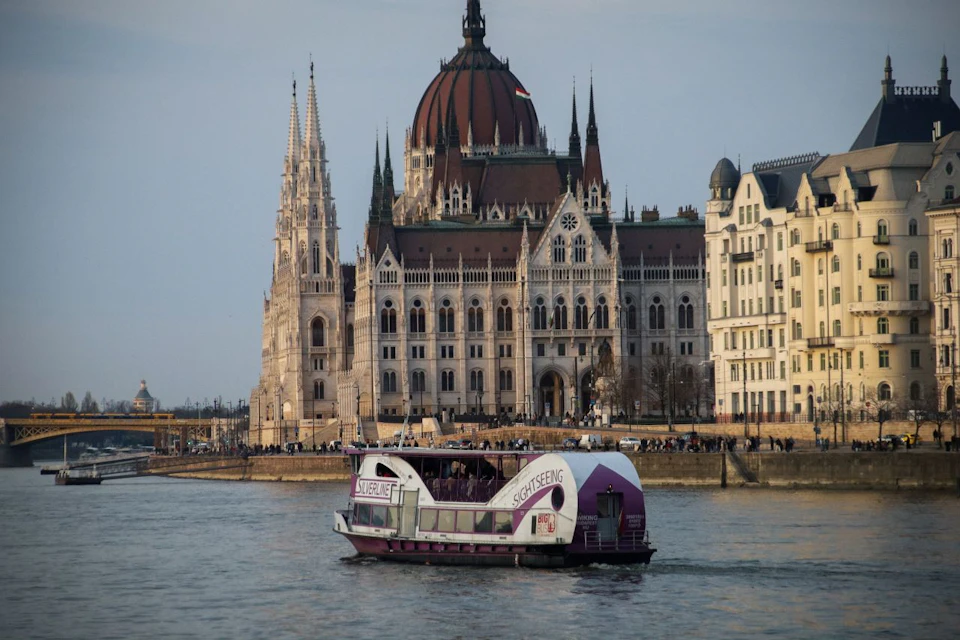 A sightseeing boat labeled "Silverline" on a river, with historic European buildings and a castle in the background under a partly cloudy sky.
