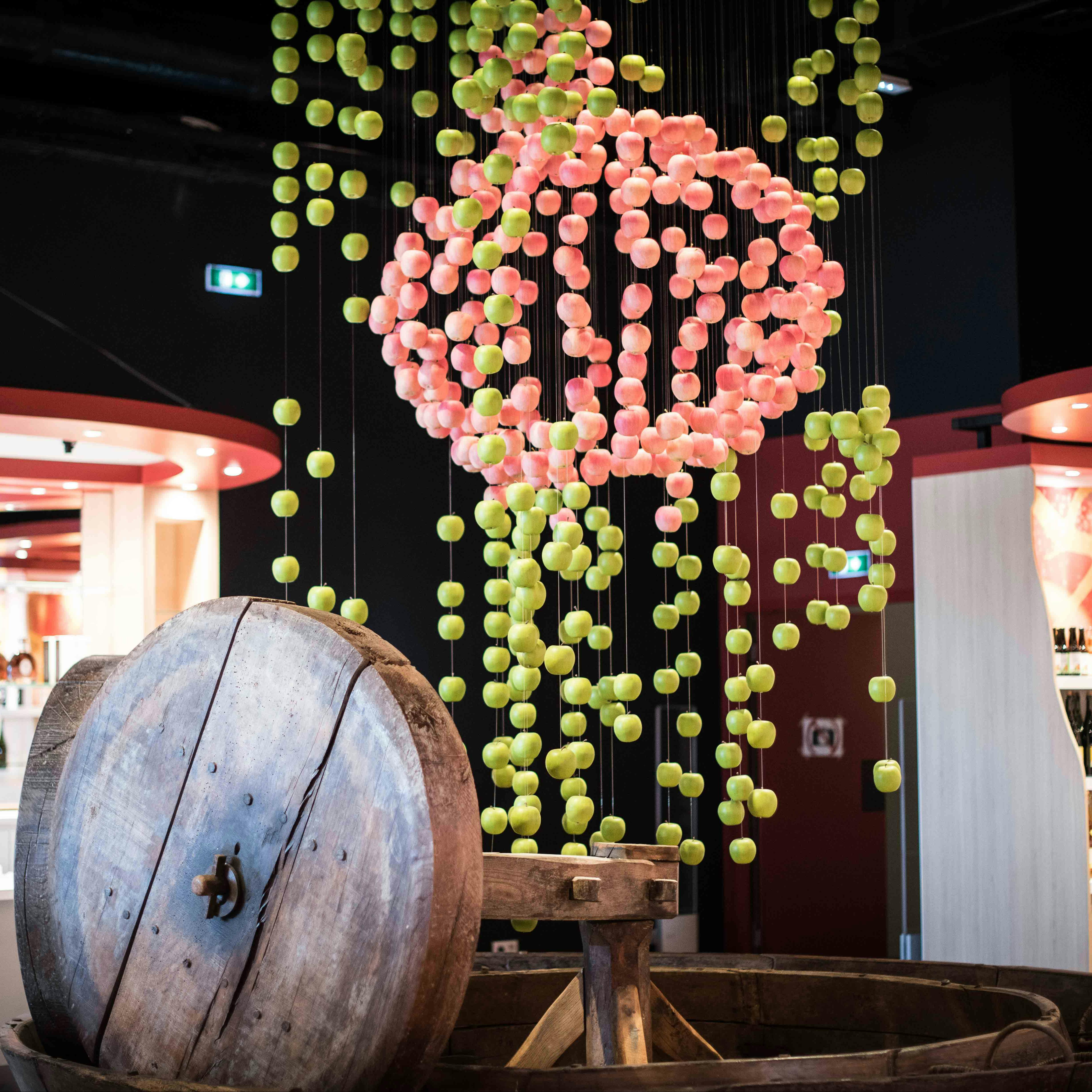 Gran barril de fusta amb una escultura d'esferes penjants de color rosa i verd davant d'un modern entorn interior.