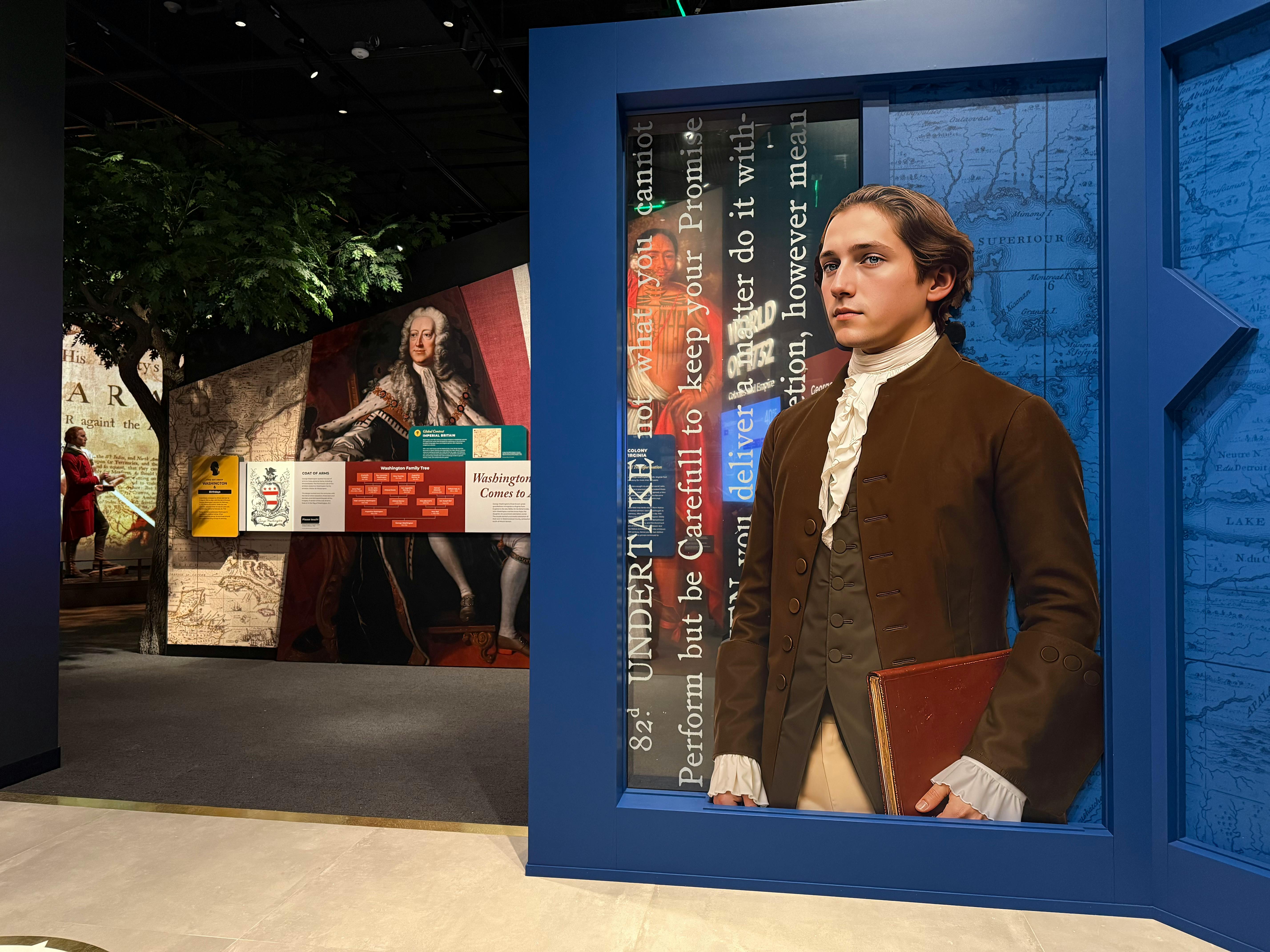 A display features a figure of a young man in historical attire holding a book, set against a backdrop with text and maps.