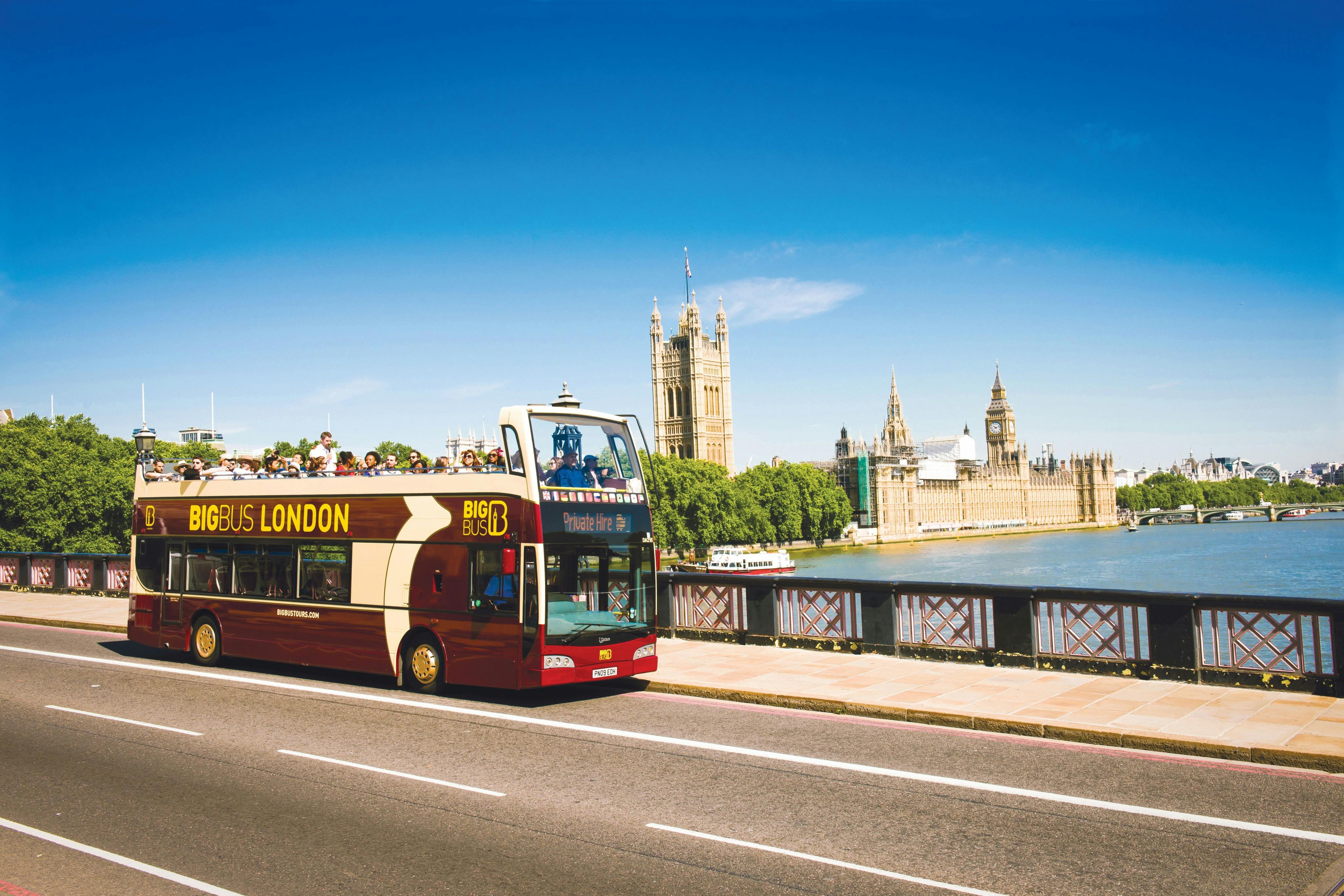 Dwupoziomowy autobus wycieczkowy jadący w słoneczny dzień w pobliżu Houses of Parliament w Londynie.
