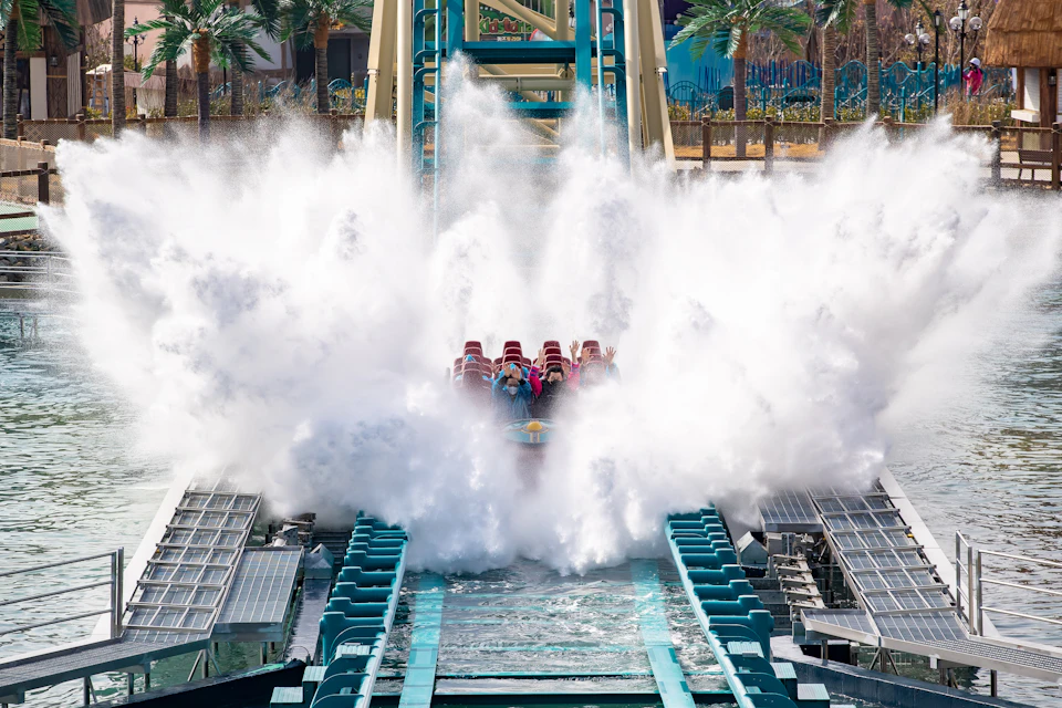 A group of people on a water ride as their vehicle splashes into the water, creating large sprays of water around them.