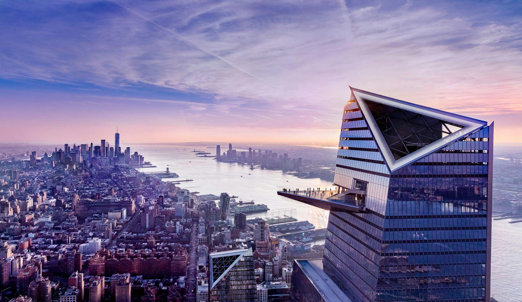Un paisaje urbano al atardecer con un moderno rascacielos que dispone de una plataforma de observación exterior con vistas a un río y al horizonte.