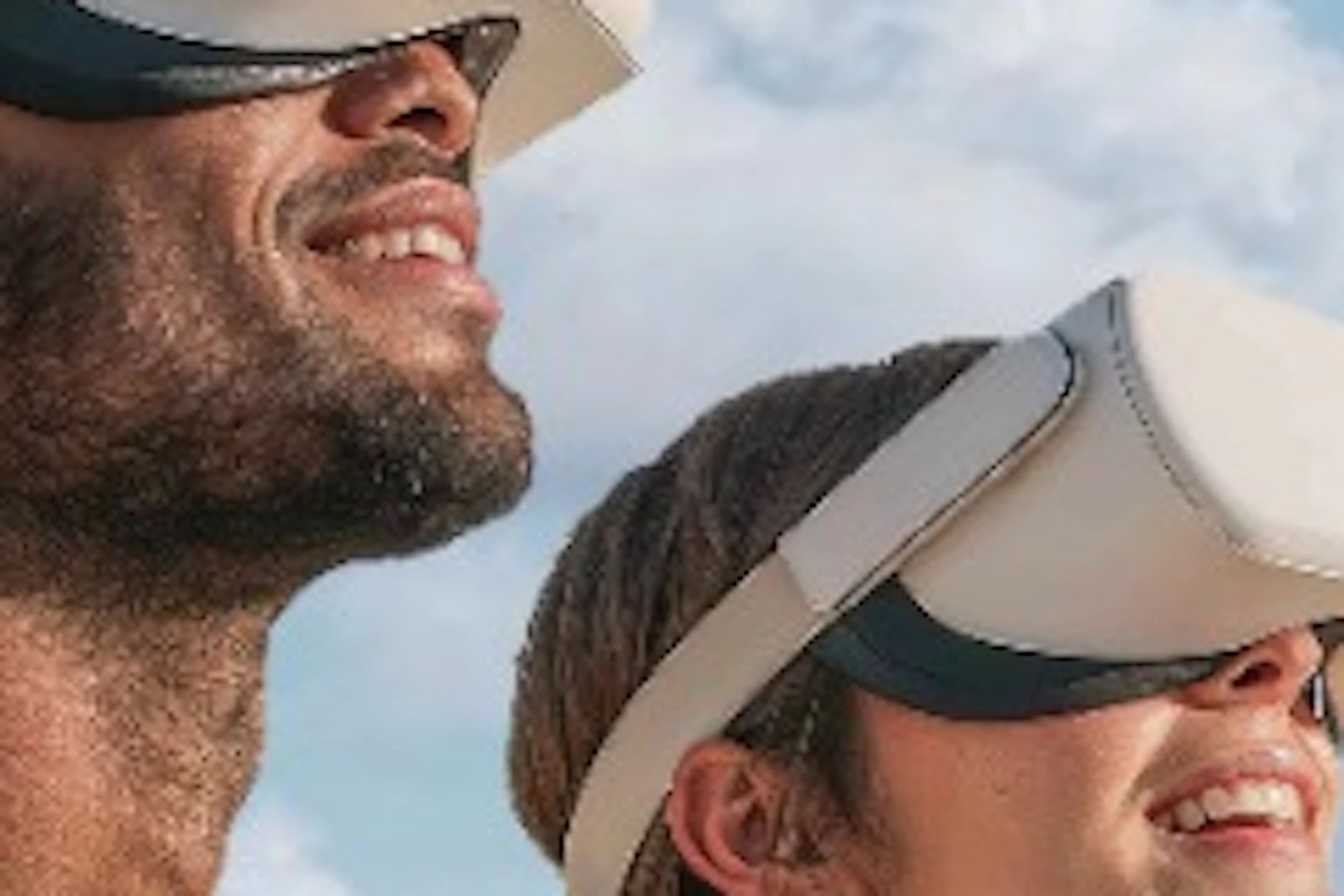 Two people wearing virtual reality headsets stand in front of a scenic backdrop featuring the Eiffel Tower and a hot air balloon.