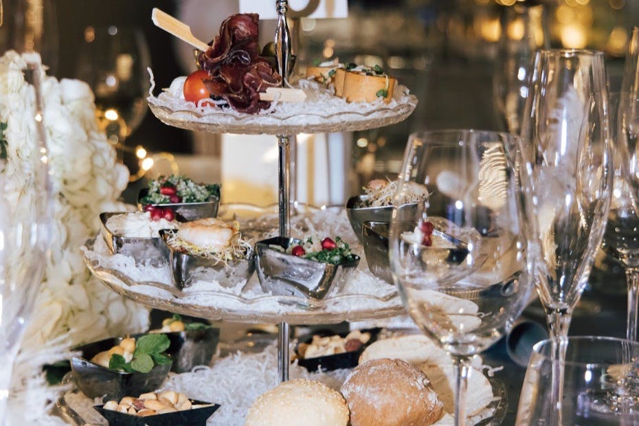 餐桌上分层摆放各种开胃菜和装饰品，周围环绕着面包、玻璃杯和装饰环境。