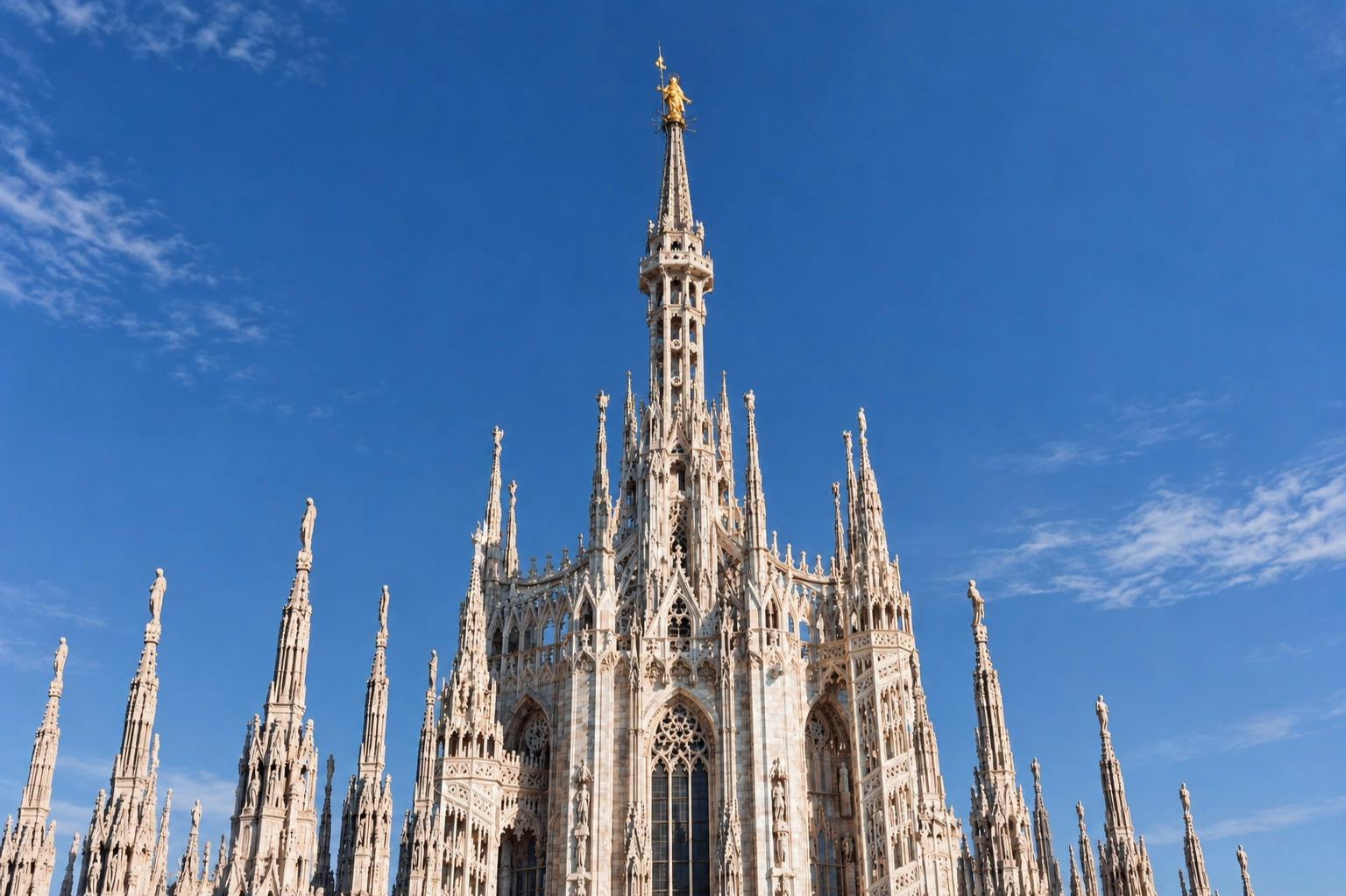 The ornate facade and spires of a Gothic-style cathedral under a clear blue sky.