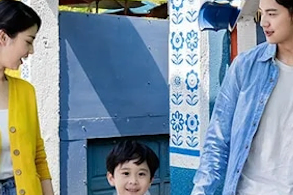 A family of three walking together through a vibrant blue-themed outdoor area with decorative pottery and a café entrance.