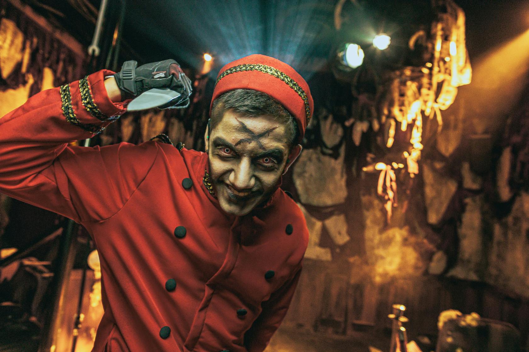 En person i bellhop-kostume med uhyggelig makeup og belysning i svagt oplyste, uhyggelige omgivelser.