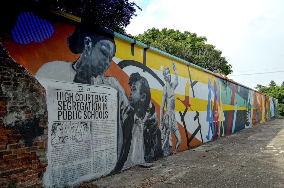 A mural depicting historical moments of the Civil Rights Movement with images of people and text about the high court banning segregation in public schools.