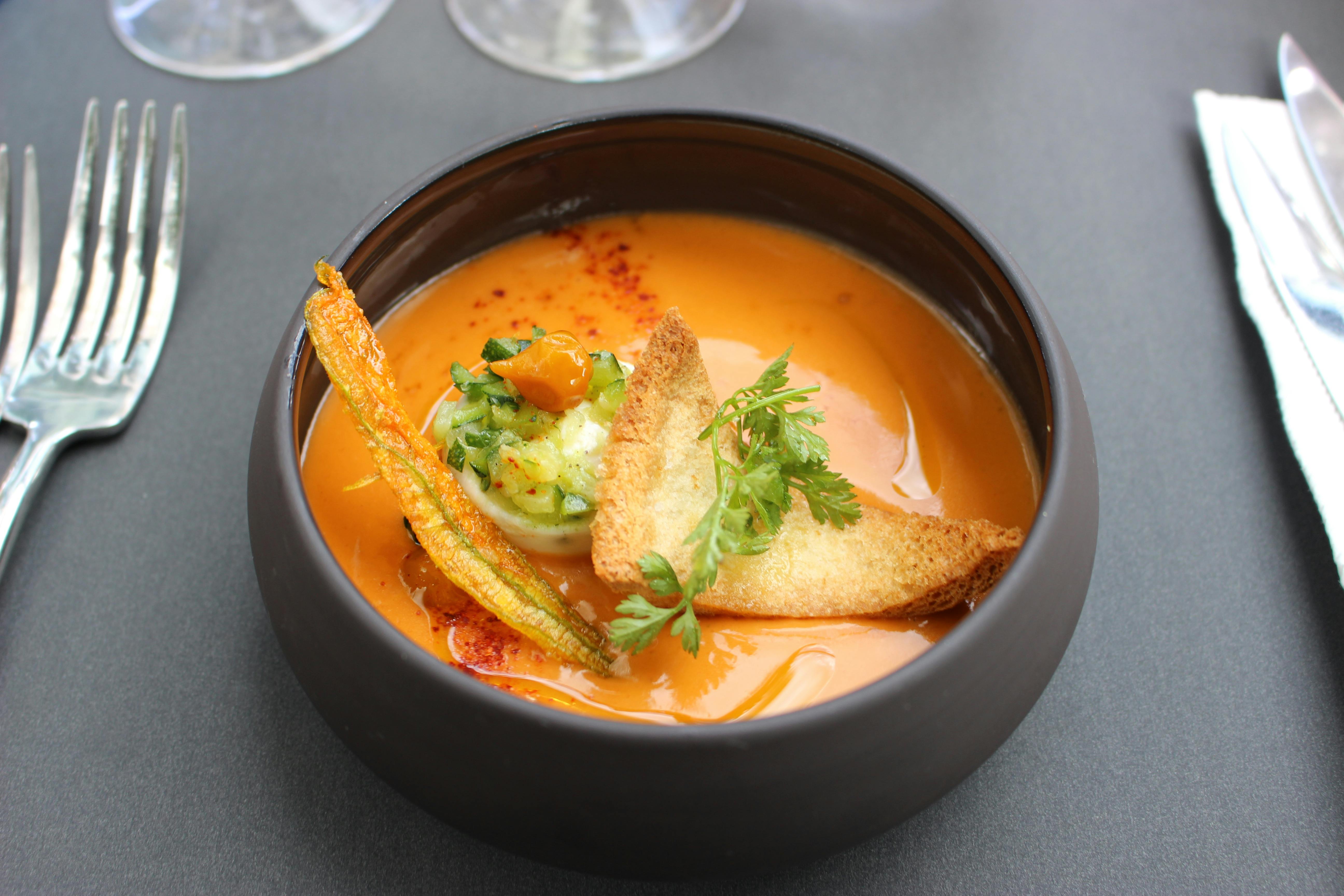 碗装有香草、面包片、南瓜花馅和西葫芦调味料的橙汤。