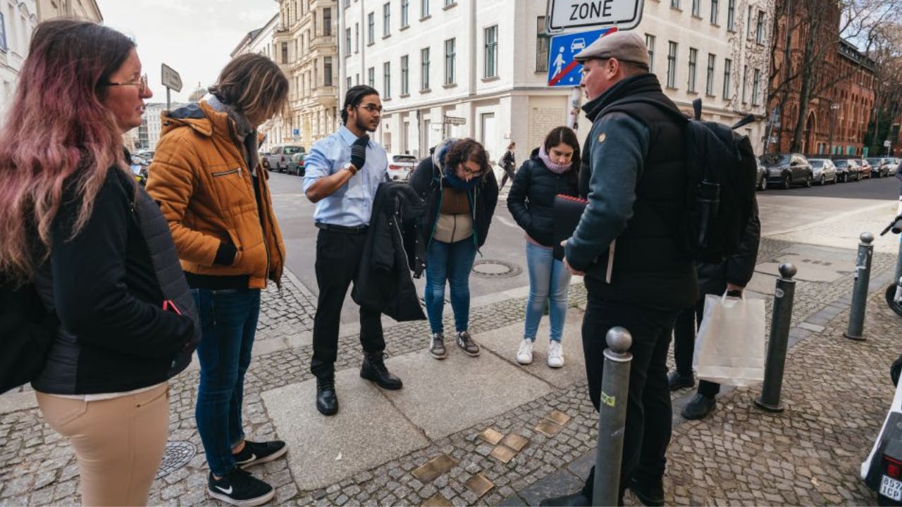 A group of four people is having a conversation on a city street corner. They are dressed in winter clothing.
