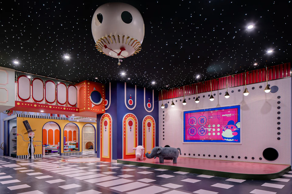 A colorful indoor playroom with starry ceiling, decorative walls, elephant statues, and a digital display on the right.