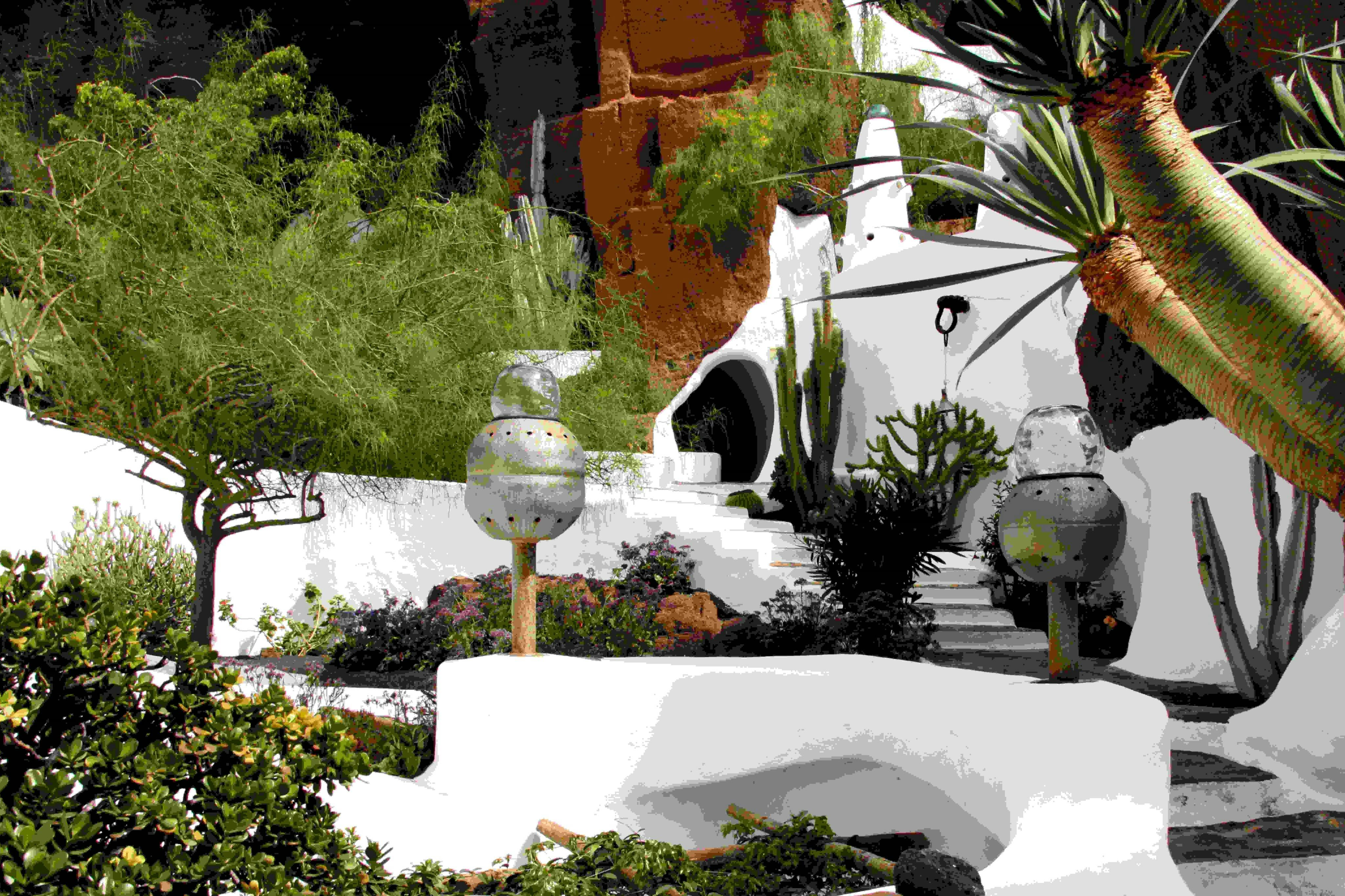 这是一座白色的穹顶形建筑，四周环绕着郁郁葱葱的绿色植被和独特的雕塑。