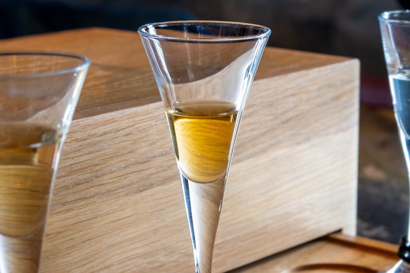 Un vaso transparente lleno de un líquido dorado, colocado sobre una superficie de madera.