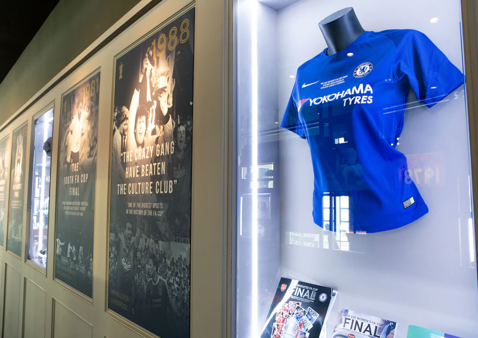 Display of sports memorabilia including a blue jersey in a glass case, posters, and magazines celebrating football achievements.