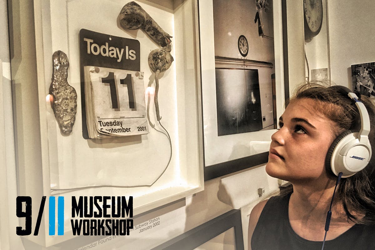 A young girl wearing headphones looks up at framed photographs and memorabilia displayed on a wall.