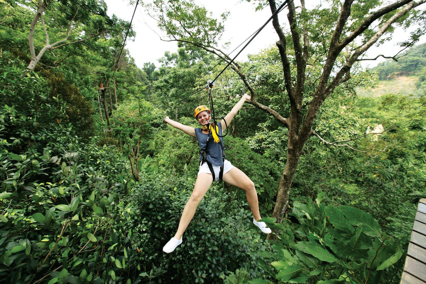 戴着头盔的人，穿过郁郁葱葱的绿色森林，微笑着伸出手臂和腿。