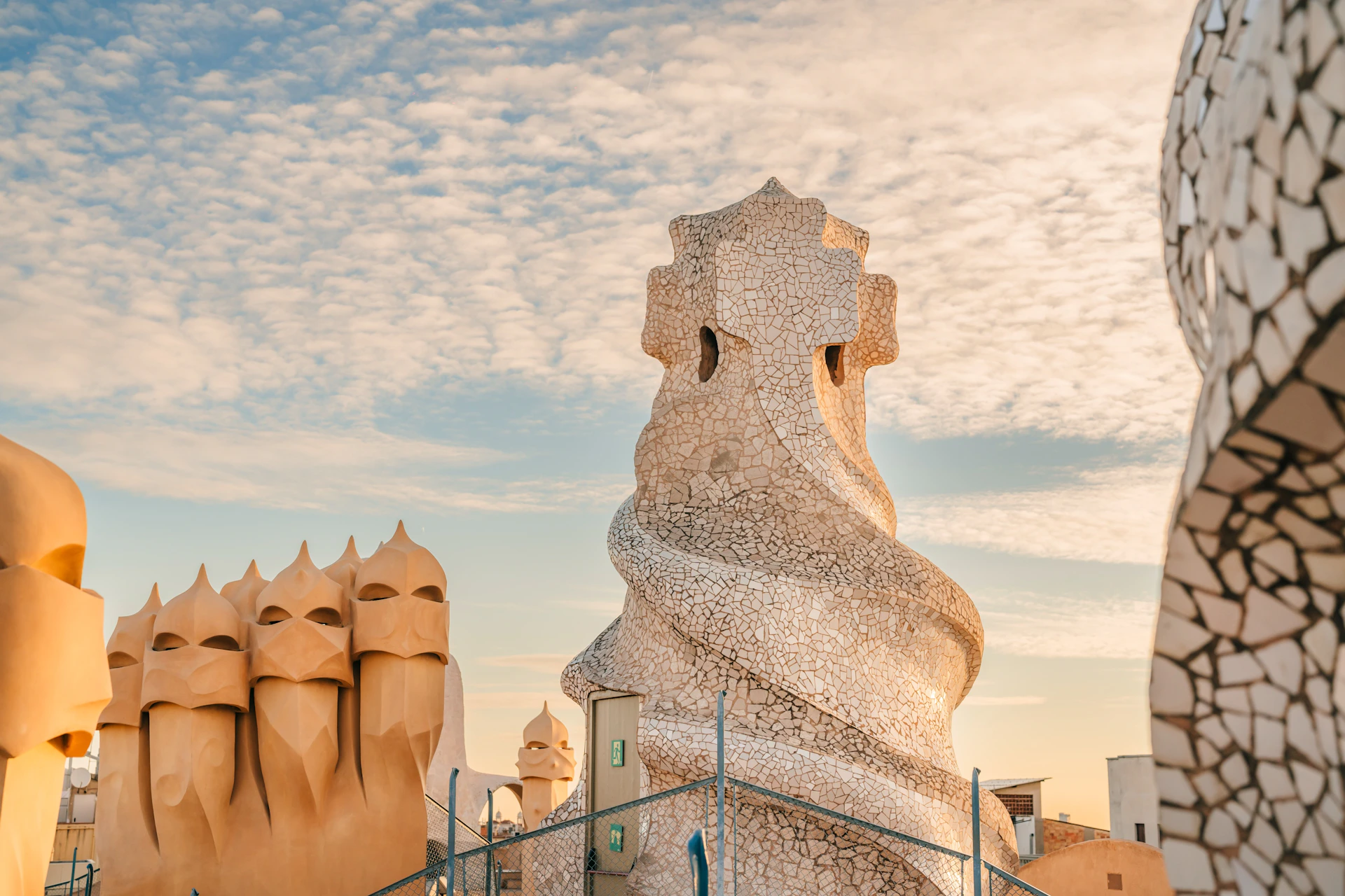 Architectural rooftop structures with unique designs under a partly cloudy sky.