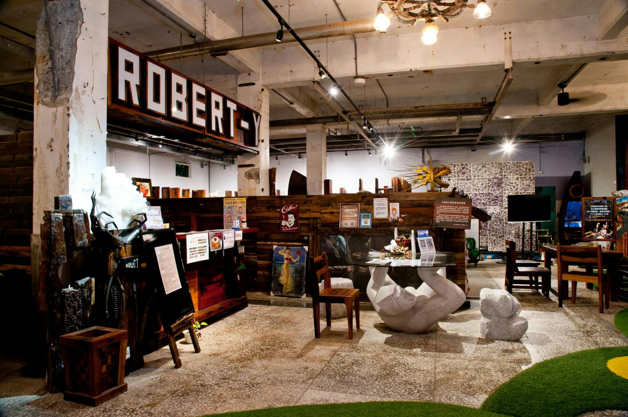 Indoor space with rustic wooden furniture, a counter with signage, a table with decorations, and a ceiling with exposed beams.